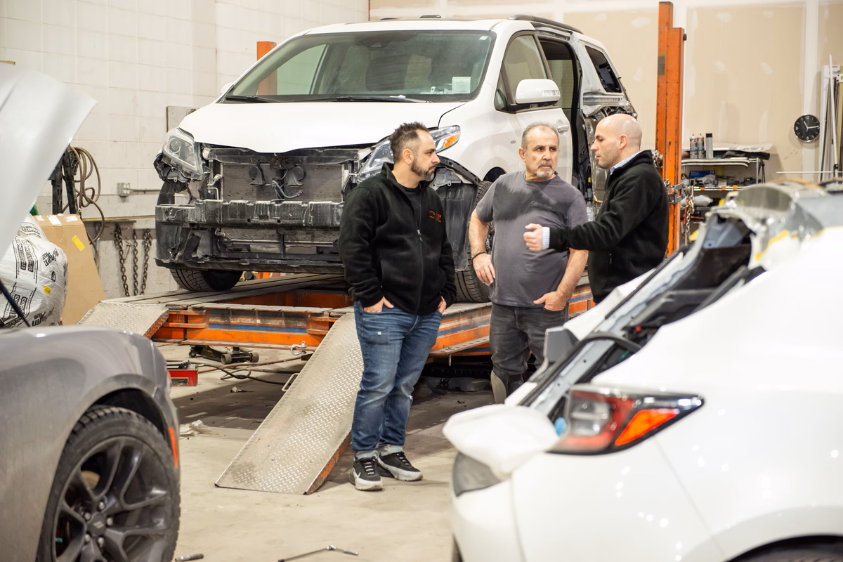 Technicians at Ultimate Car Care Group working on a customer vehicle on the frame rack.