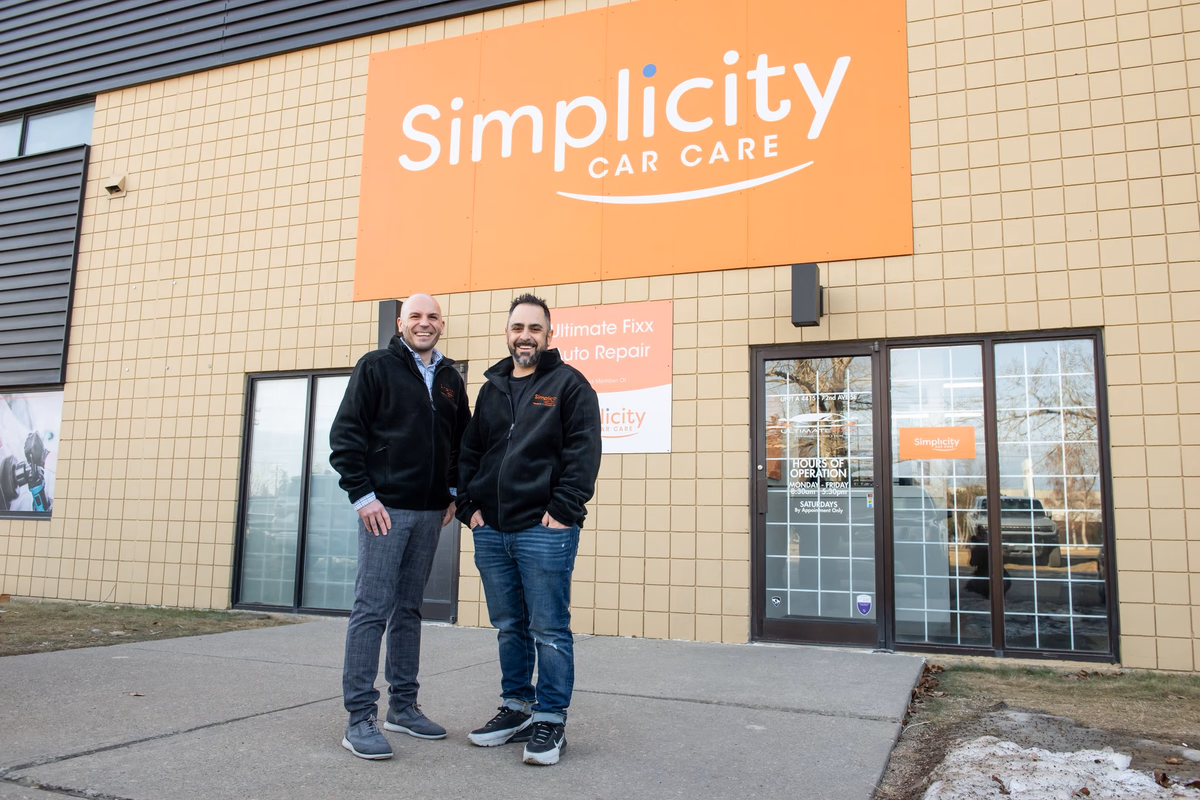 The original shop's storefront, with the Simplicity Car Care wall sign above the smaller Ultimate Fixx Auto Repair sign.